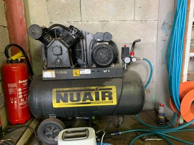 un compresseur noir posé dans un garage à côté d'autres outils