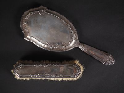 deux brosses à cheveux anciennes en métal argenté et un miroir sur fond noir