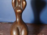 sculpture représentant une figure féminine posée sur une table, avec l'ombre d'une personne en arrière-plan