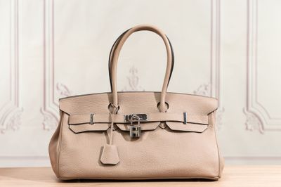 a beige leather handbag sitting on top of a wooden table