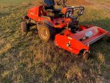 a red lawn mower sitting on top of a lush green field