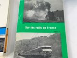 two books on a table with a train in the background