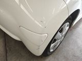 a close up of a white car with a denting on it