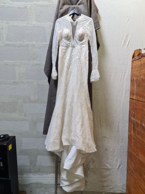 a wedding dress hanging on a clothes rack in a room