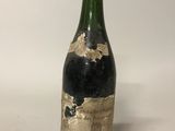 une vieille bouteille de vin posée sur une table blanche