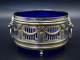an antique silver and blue glass bowl sitting on a black surface