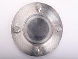 a silver plate on a white surface with a black center