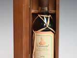 an old bottle of wine in a wooden box on a white surface