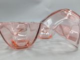 four pink glass bowls sitting on a white surface