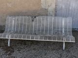 a white metal bench sitting in front of a wall