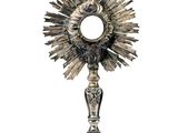 une image représentant une statue en argent représentant un soleil surmonté d'une croix
