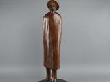 a wooden statue of a woman in a hat and coat