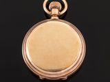 a close up of a gold pocket watch on a black surface