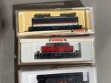 trois boîtes de petits trains empilées les unes sur les autres sur une table
