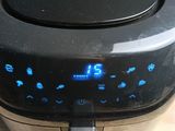 une friteuse à air chaud noire posée sur une table en bois