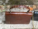 a brown purse and a black purse sitting on the ground