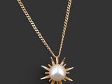 un collier en or avec un pendentif en forme de perle blanche, monté sur une chaîne en or