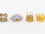 three gold crowns and a diamond ring on a white background