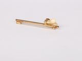 gold plated hair pin with a tooth on it on a white surface