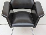 an image of a black leather chair against a white wall