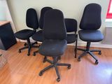four black office chairs in a room with a wood floor