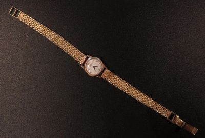 an image of a watch on a black surface with a black background
