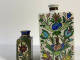 two small vases sitting next to each other on a white surface