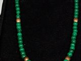 a close up of a green beaded necklace in a black case