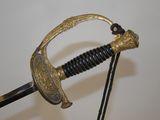 a gold colored sword with a black handle on a white background