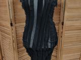 a black dress on a mannequin stand in front of a wooden wall