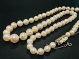 gros plan d'un collier de perles blanches sur une surface noire