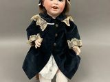 poupée en porcelaine représentant une petite fille vêtue d'un manteau bleu et d'un pantalon blanc