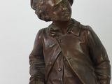 a bronze statue of a boy with a hat and jacket
