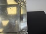 a silver plate on a black table with a shadow on the wall