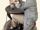 a figurine of a man sitting at a table with a bottle