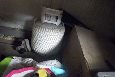 des toilettes situées dans un coin d'une pièce où il y a plein de choses par terre