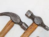two hammers and a nail on a white surface