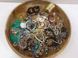 a wooden bowl filled with lots of jewelry on a table