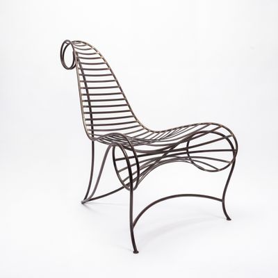 une chaise en fer avec un dossier et une assise incurvés, sur fond blanc