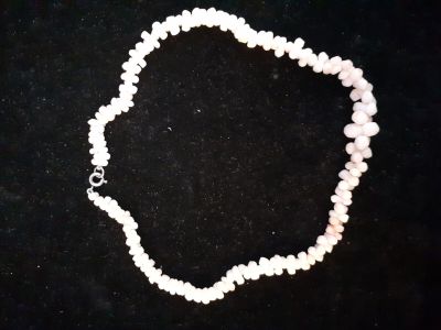 a close up of a white beaded necklace on a black surface