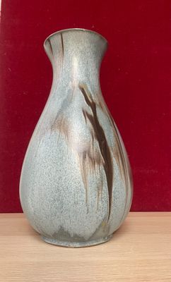 a blue vase sitting on a table with a red wall behind it