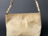 a close up of a beige purse with a beaded handle