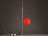 a red heart shaped lamp on a metal stand next to a wire