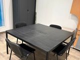 une table et des chaises noires dans une pièce dotée d'une porte-fenêtre coulissante