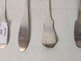 four spoons and a fork are lined up on a table
