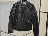 une veste en cuir noir accrochée à un porte-manteau dans une pièce