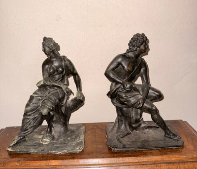une paire de statues en bronze représentant un homme et une femme assis sur un rocher