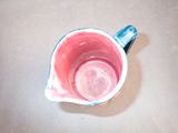 a pink cup with a blue handle on a table
