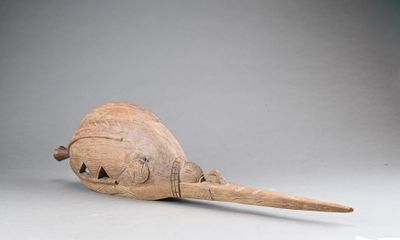 un vieil oiseau en bois au long bec, posé sur une surface grise