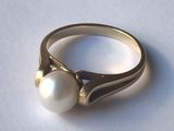 a ring with a pearl on it sitting on a table
